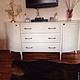 White oval chest of drawers on curved legs. Ample drawers make it the perfect place for storing clothes or collectibles.